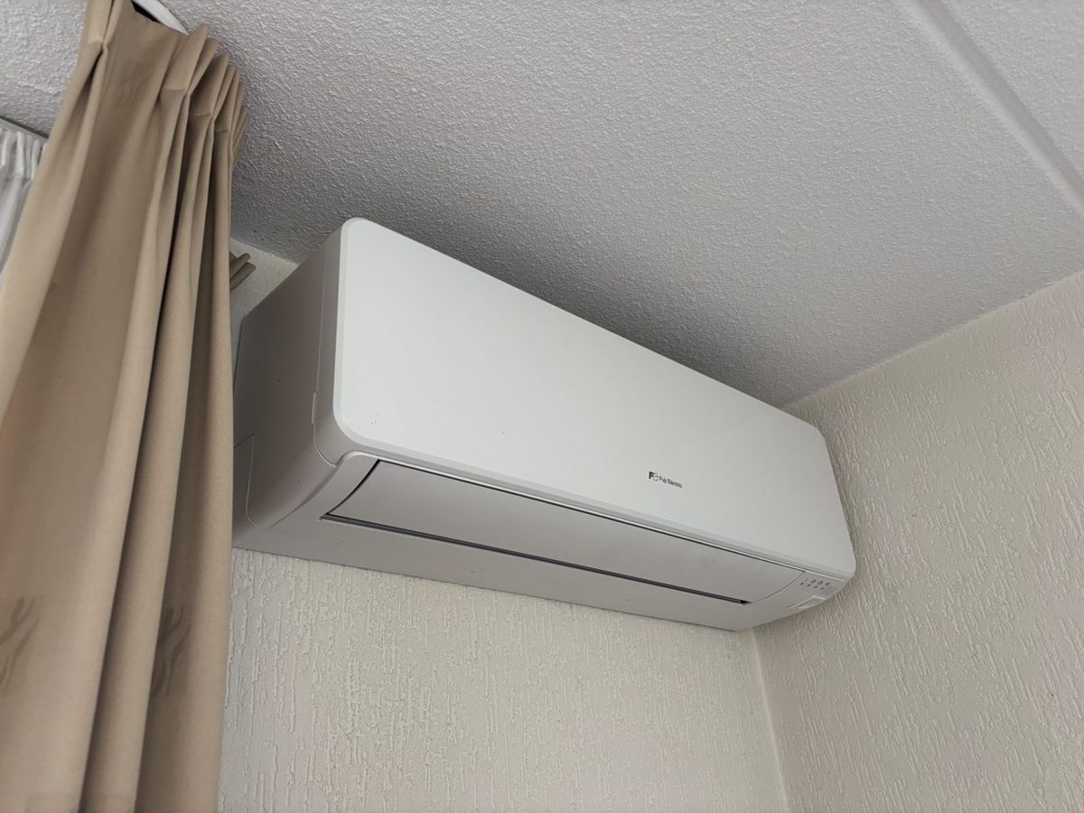 Wit Fuji Electric wandmodel in de hoek onder het plafond, schuin aanzicht